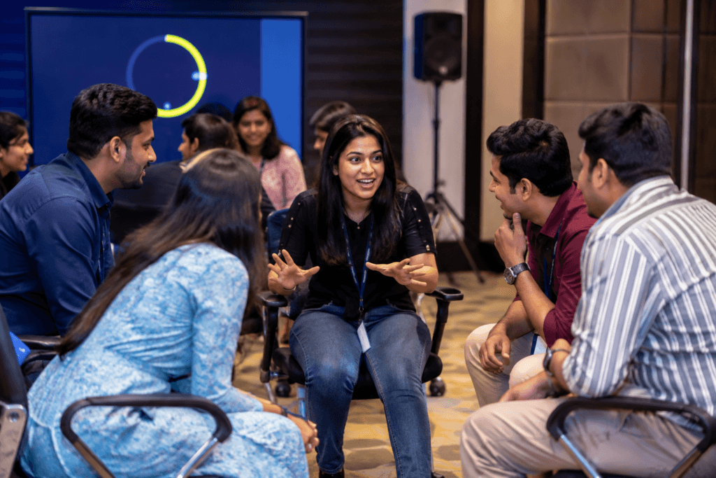 Corporate employees playing an AI Digital Taboo team building activity using an interactive digital platform while collaborating to solve communication challenges during an office event.