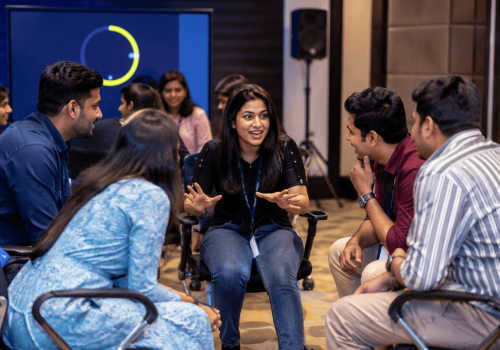 Corporate employees playing an AI Digital Taboo team building activity using an interactive digital platform while collaborating to solve communication challenges during an office event.