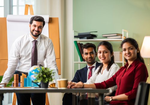 Indian asian young business professionals using laptop on desk discussing strategy
